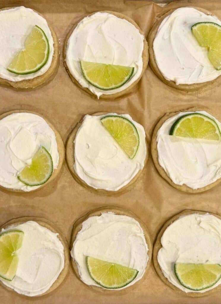 Closeup of frosted cookies with lime slices on top.