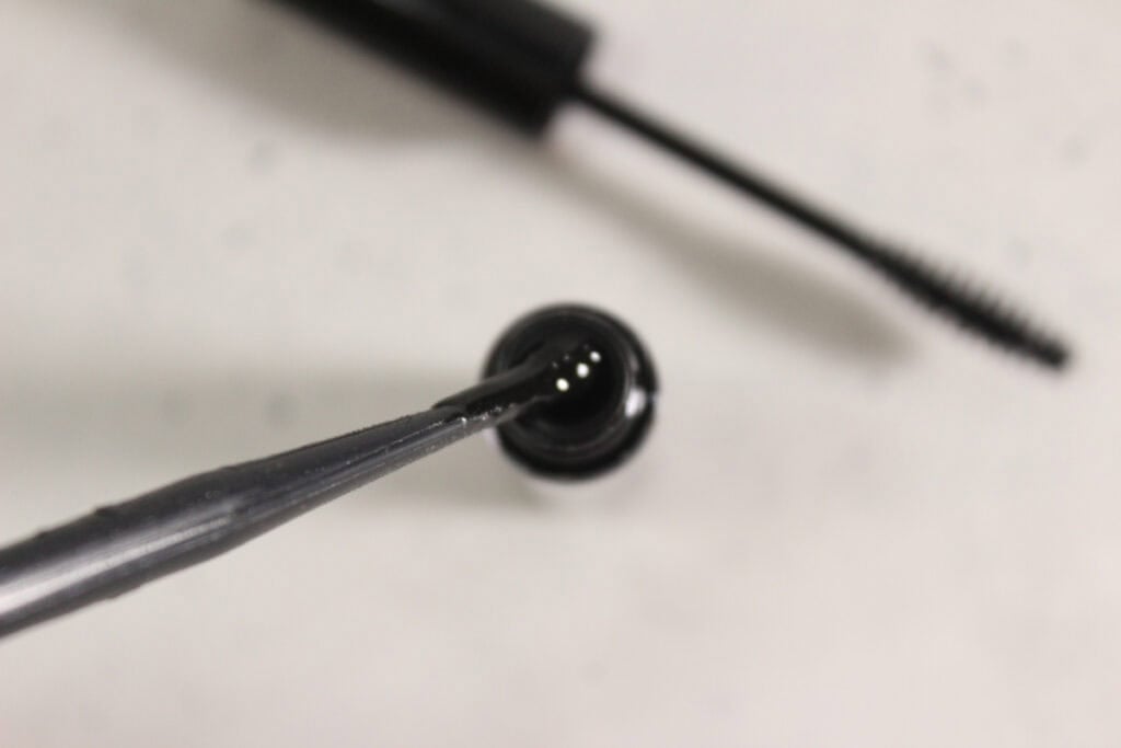 Using pipette to add mascara mixture to mascara tube.