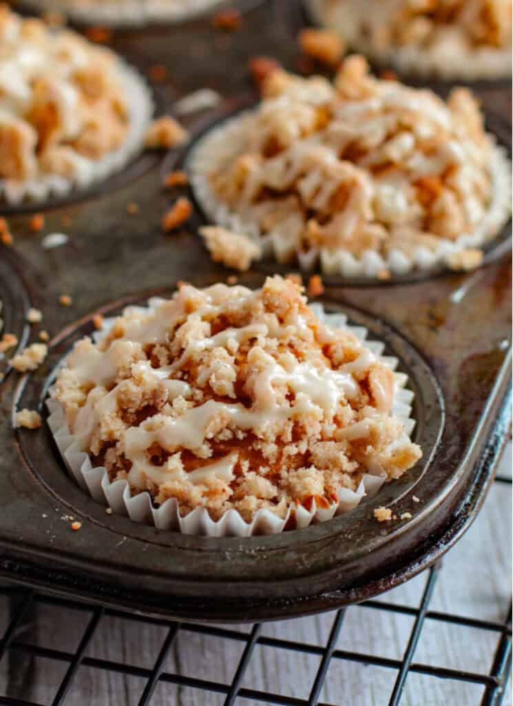 Pumpkin muffins with crumb topping and maple glaze in muffin tins.