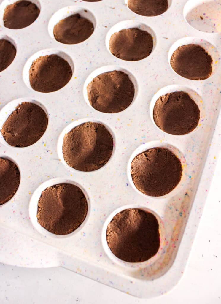 Brownie mixture pressed into mini muffin tin.