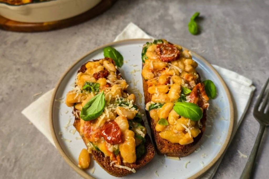 Miso beans on two pieces of sourdough toast on a plate with more toppings.