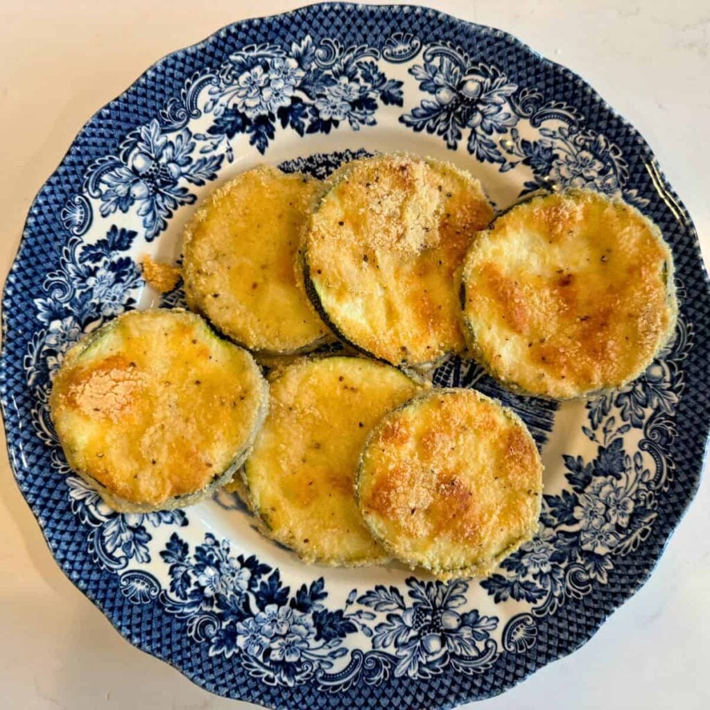 Zucchini crisps with sourdough breading on a blue and white plate.
