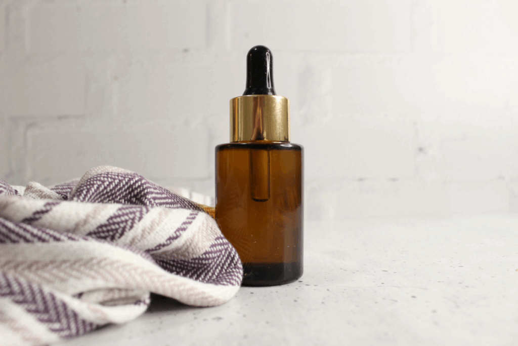 Image of bottle of mascara remover recipe with striped tea towel on a speckled countertop.